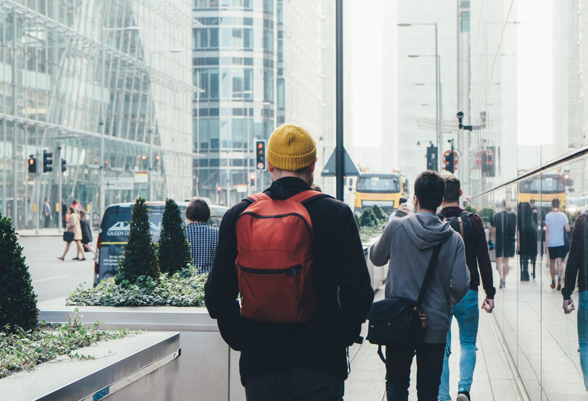 man with backback walking on urban sidewalk